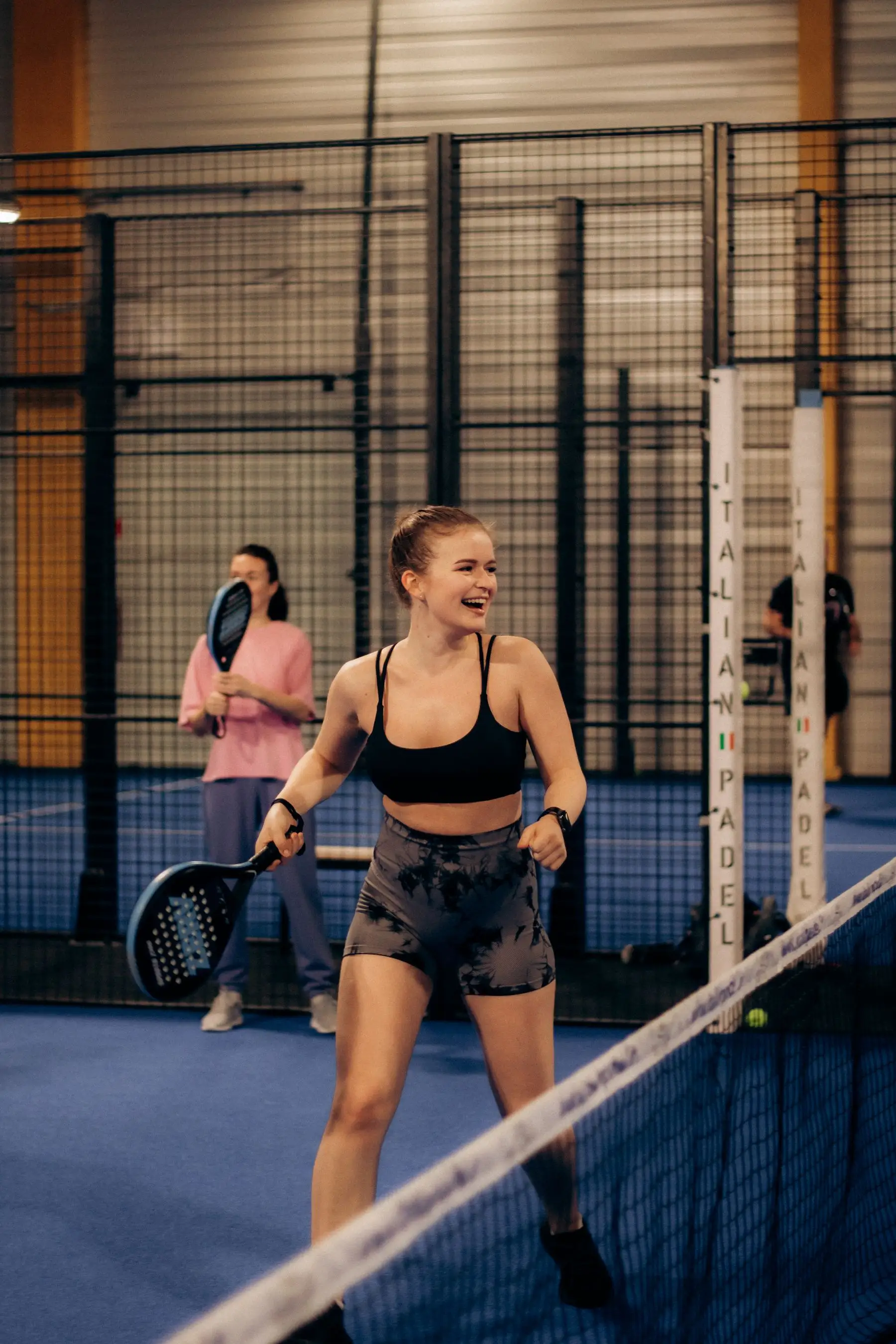 Une joueuse sourit pendant un match de padel entre amis