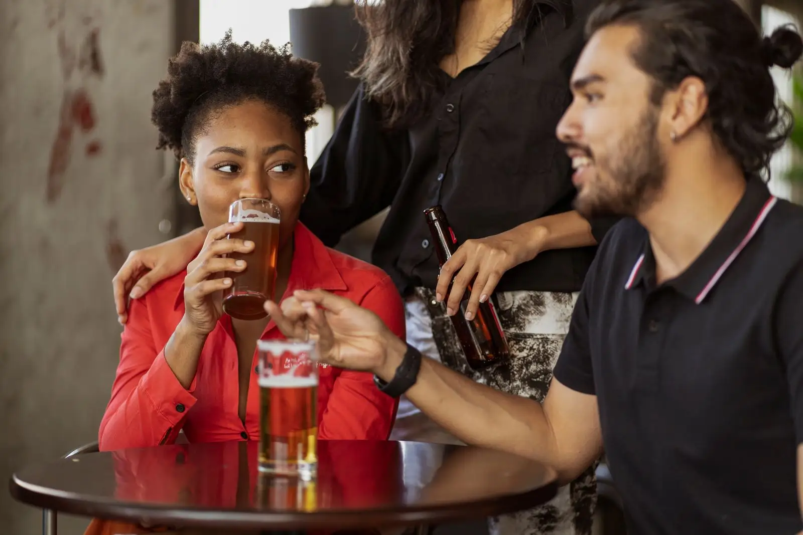 Des amis rient autour d’une table, verre à la main